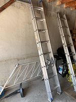 Aluminum extension ladder leaning against wall showing full length and base support.