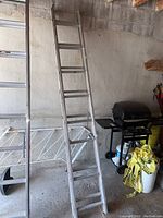 Aluminum extension ladder leaning against a wall showing full length and environment.