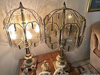 Photo showing both vintage table lamps on a wooden surface, each with curved glass panel shades and metal/stone bases.