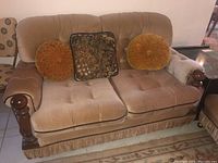 Front view of beige fabric loveseat with tufted cushions and decorative pillows.