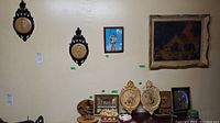 Wall mounted framed prints and plaques, with key hangers below on wall and shelf