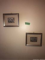 Two silver-framed prints hung on wall with size label 5.5x7