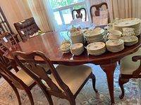 Wood dining table with chairs around it and various dishes on top, showing overall table shape, size and condition.
