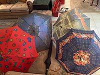 Five umbrellas displayed on couch, showing colors and general patterns.