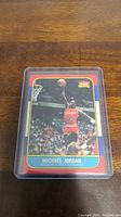 Front view of the Michael Jordan rookie reprint basketball card encased in a plastic protective sleeve, showing Michael Jordan in Chicago Bulls uniform during a slam dunk.
