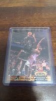 Close-up photo of a 1992-93 Stadium Club basketball rookie card featuring Shaquille O'Neal in a plastic protective case showing O'Neal making a jump shot with crowd and opponent in the background.