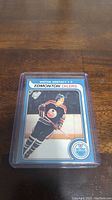 Photo of Wayne Gretzky Edmonton Oilers rookie reprint hockey card in protective holder on wooden surface