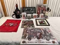 Full view of all items in the San Francisco 49ers and Giants sports memorabilia collection showing flag, mugs, plaques, framed photo, bobblehead, poster, and collectible block.