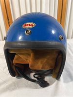 Front view of blue Bell helmet with visible logo, brown interior lining and chin strap.
