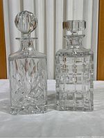 Two crystal decanters side by side showing overall shape and cut patterns with stoppers in place