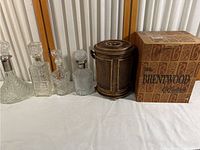 Overview of four crystal decanters arranged from largest to smallest and vintage metal ice bucket with original box