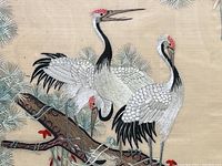 Close-up of three embroidered Japanese cranes with detailed stitching on wings, legs, and red crests on heads.