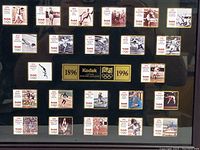 Close-up view of pins arranged in rows with Kodak and Olympic logos, showing athletes and event years from 1896 to 1996.