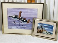Both framed prints displayed on a cloth surface, showing size difference and gold-toned frames
