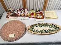 View showing all items in the lot, including kitchen towels, handmade round placemats, ceramic platter, and plates.