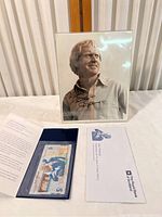 Full lot view showing autographed Jack Nicklaus photo in protective sleeve standing upright behind commemorative Scottish note and certificate in blue holder.