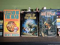 Front cover view of three science fiction paperbacks: Legend of the Dead by Micah S. Hackler, Dark of the Moon and God Stalk by P.C. Hodgell, showing cover art and condition.