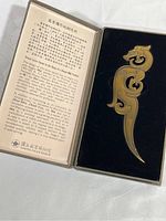 Letter opener placed in custom fitted box alongside detailed printed description with Chinese text and English explanation from the National Palace Museum.