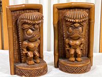 Pair of vintage carved wooden tiki bookends with bamboo-style frames and geometric patterned bases.