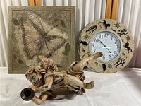 Three rustic composite patio decor items: butterfly plaque, cherub statue, and decorative wall clock.