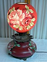 Front view of the vintage glass globe lamp showcasing the hand painted red floral globe on top and matching floral base.