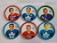 Top view showing six Sherriff hockey coin player tokens with colorful rims and vintage player images.