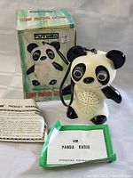 Panda bear-shaped transistor radio with original box, instruction manual, and warranty paper visible.