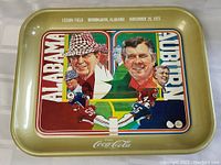 Top-down photo of the Coca-Cola metal tray showing detailed artwork of the 1975 Alabama vs Auburn football game at Legion Field, Birmingham, Alabama, dated November 29, 1975.