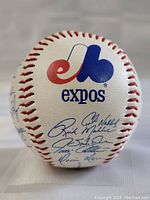 Front panel of the vintage 1980s Montreal Expos promotional baseball showing the red and blue Expos logo with several blue ink autographs beneath it.