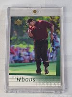 Front view of 2001 Upper Deck Tiger Woods rookie card in thick protective plastic case, showing Tiger Woods celebrating on a golf course.