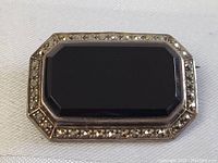 Close-up image of the antique sterling silver Art Deco brooch pin showing the rectangular black onyx center stone with a border of marcasite stones.