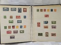 Two-page spread of Canadian postage stamps arranged in rows within a photo album. Various denominations and colors visible with some stamps postmarked.