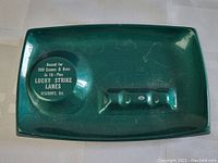 Top-down photo showing green rectangular aluminum ashtray with bowling award inscription.