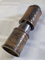 Collapsible brass nautical telescope with stitched leather wrap and Royal Marine markings, angled top view showing extended segment