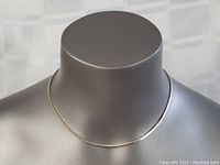 Front view of the sterling silver necklace displayed on a gray mannequin bust showing full length and slight shine.