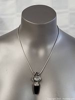 Full view of silver pendant necklace displayed on bust showing pendant and chain.