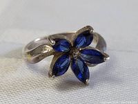Front angle showing the sapphire flower design with five marquise-cut blue stones and central small clear stone on sterling silver band.
