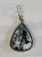 Front view of sterling silver pendant showing marbled black and white stone in teardrop shape with decorative beaded silver bezel.