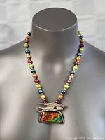 Front view of the necklace on a display bust showing the multicolor beads and the unique pendant with an iridescent stone and abstract silver overlay.