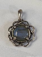 Front view of vintage sterling silver pendant featuring a round Eilat stone held by four prongs and an intricate silver vine frame.