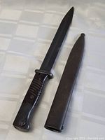 Bayonet and scabbard laid side by side on tablecloth