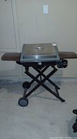 Front view of the portable Cuisinart BBQ grill with folding legs and wheels.
