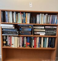Books arranged on shelves with visible titles covering a wide range of topics including history, politics, science, and health. Several Stephen Hawking books are included.