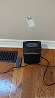 Speaker and remote on hardwood floor with lot tag visible