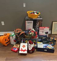 Lot arranged on floor showing Halloween pumpkin decor, a pumpkin mask, boxes of LED Christmas lights, light-up snowman yard decoration, ribbons, small Santa figure, and Christmas cards.