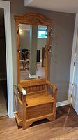 Front view showing carved top crest, mirror, bench seat and hooks