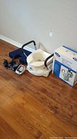 Wide shot of blood pressure monitor, cushion seat, stethoscope, raised toilet seat box on wooden floor