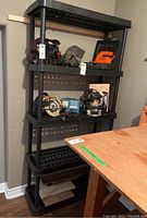 Front view of the black resin 5 level shelf measuring approximately 35x13x73, showing ventilated shelves and cylindrical corner posts.
