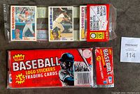 Photo showing 1982 Fleer unopened rack pack with three 15-card packs inside, along with sealed 1984 O-Pee-Chee rack pack featuring Ryne Sandberg on front.