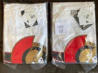 Photo showing 2 white Ottawa Senators t-shirts sealed in original plastic packaging with visible large team logo on front.